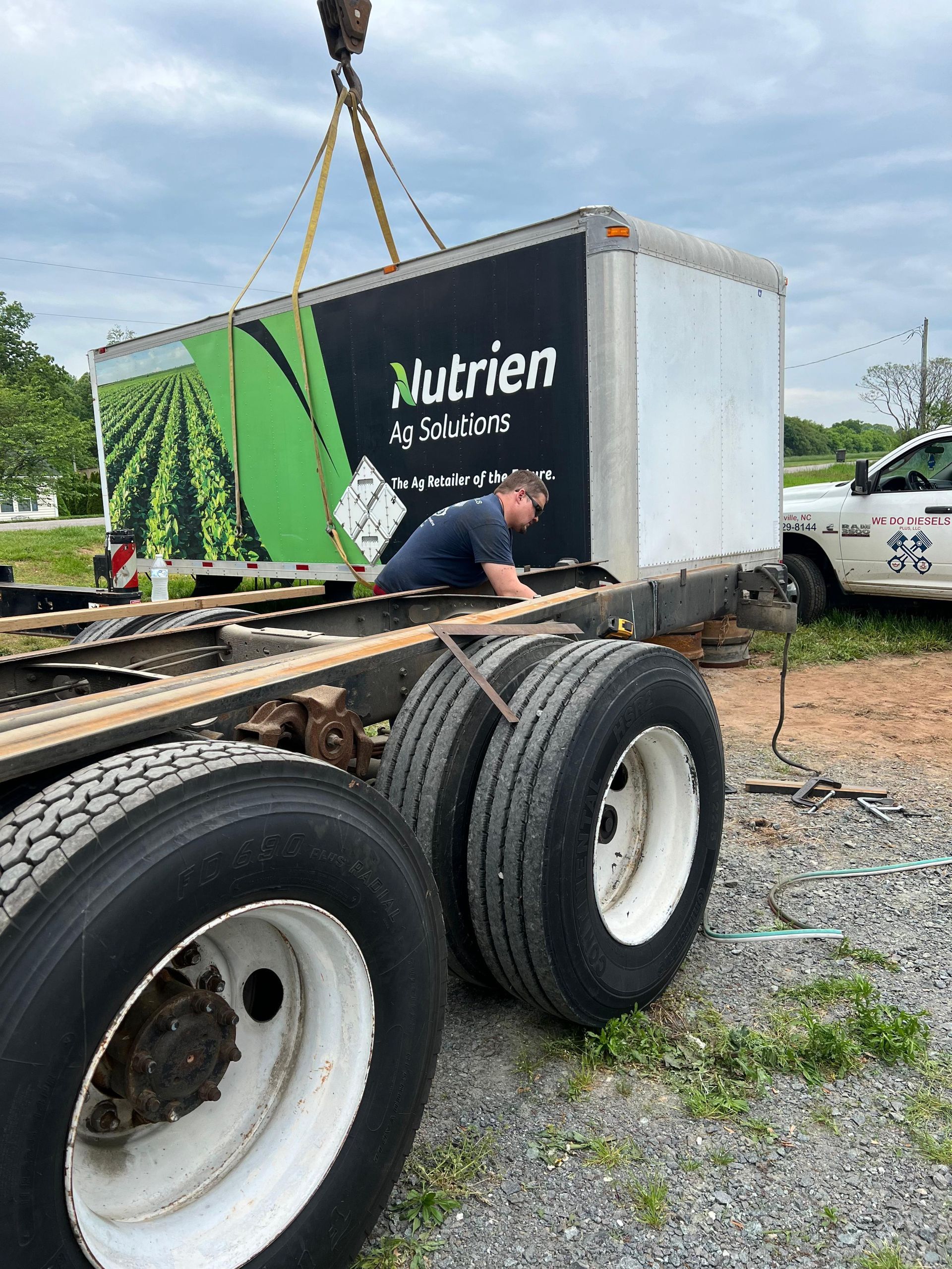A box truck body being lifted off its chassis by a crane. 