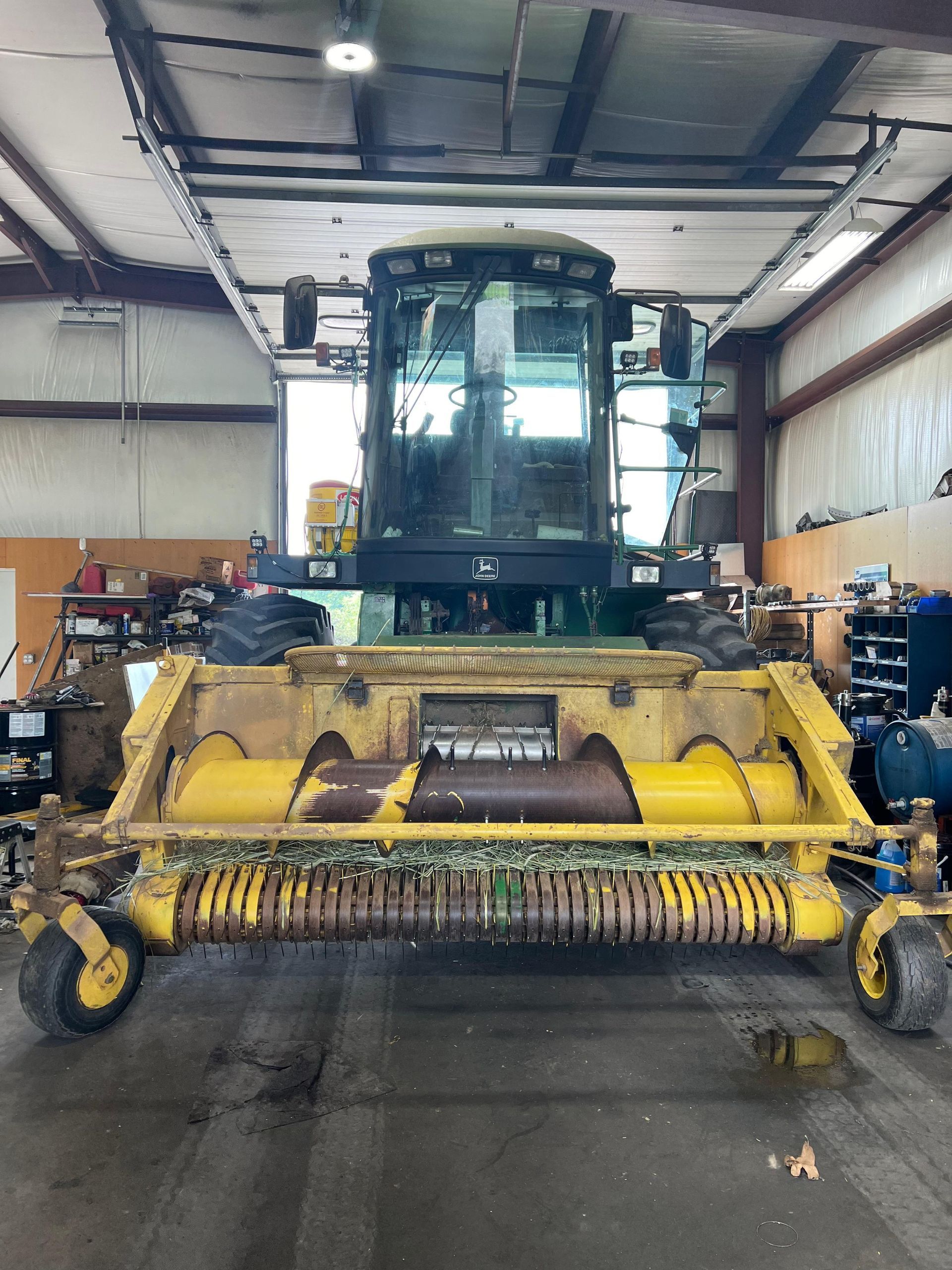 Yellow and green combine harvester inside a workshop. 