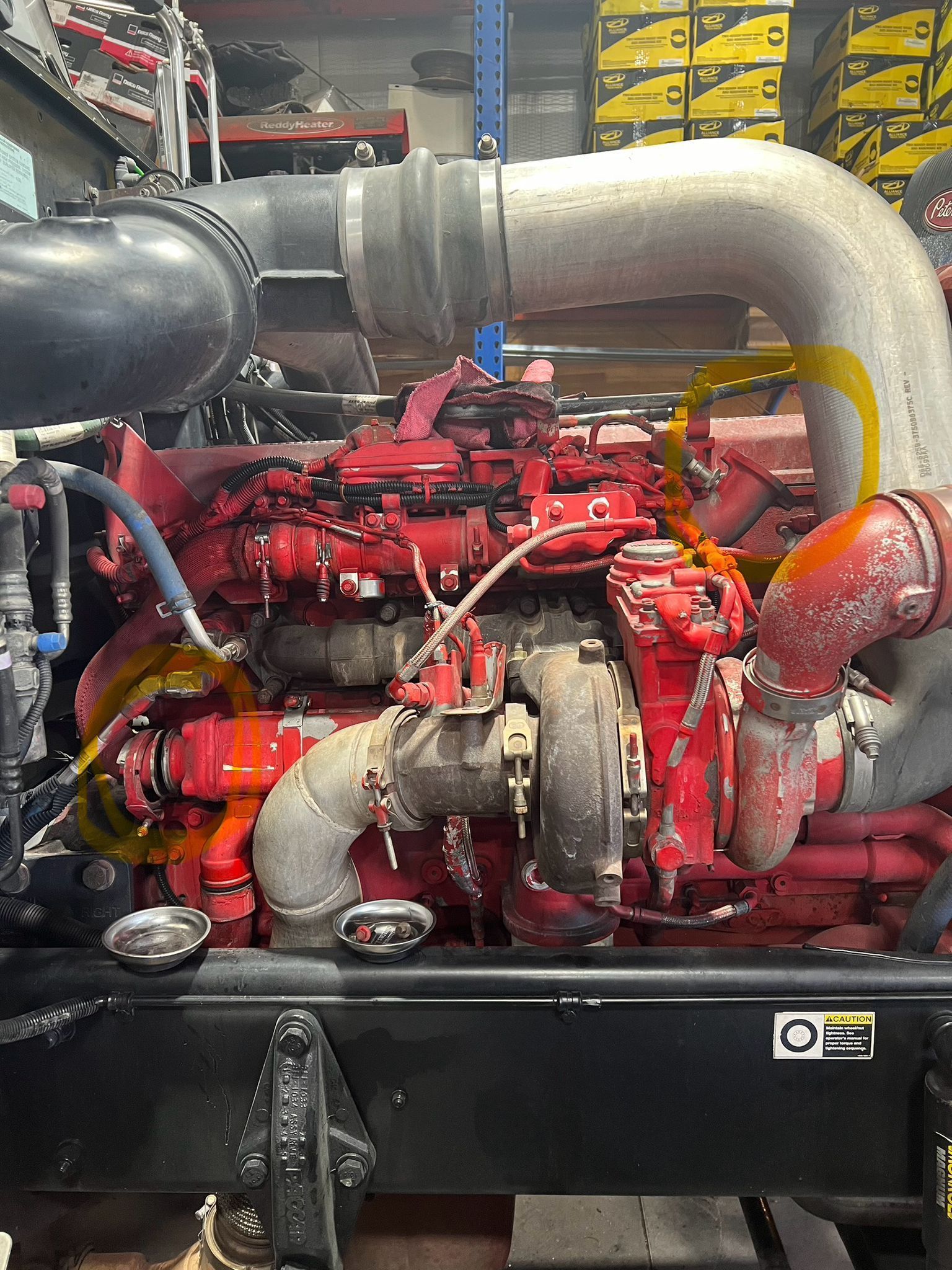 Red engine with black and silver pipes in an engine compartment.