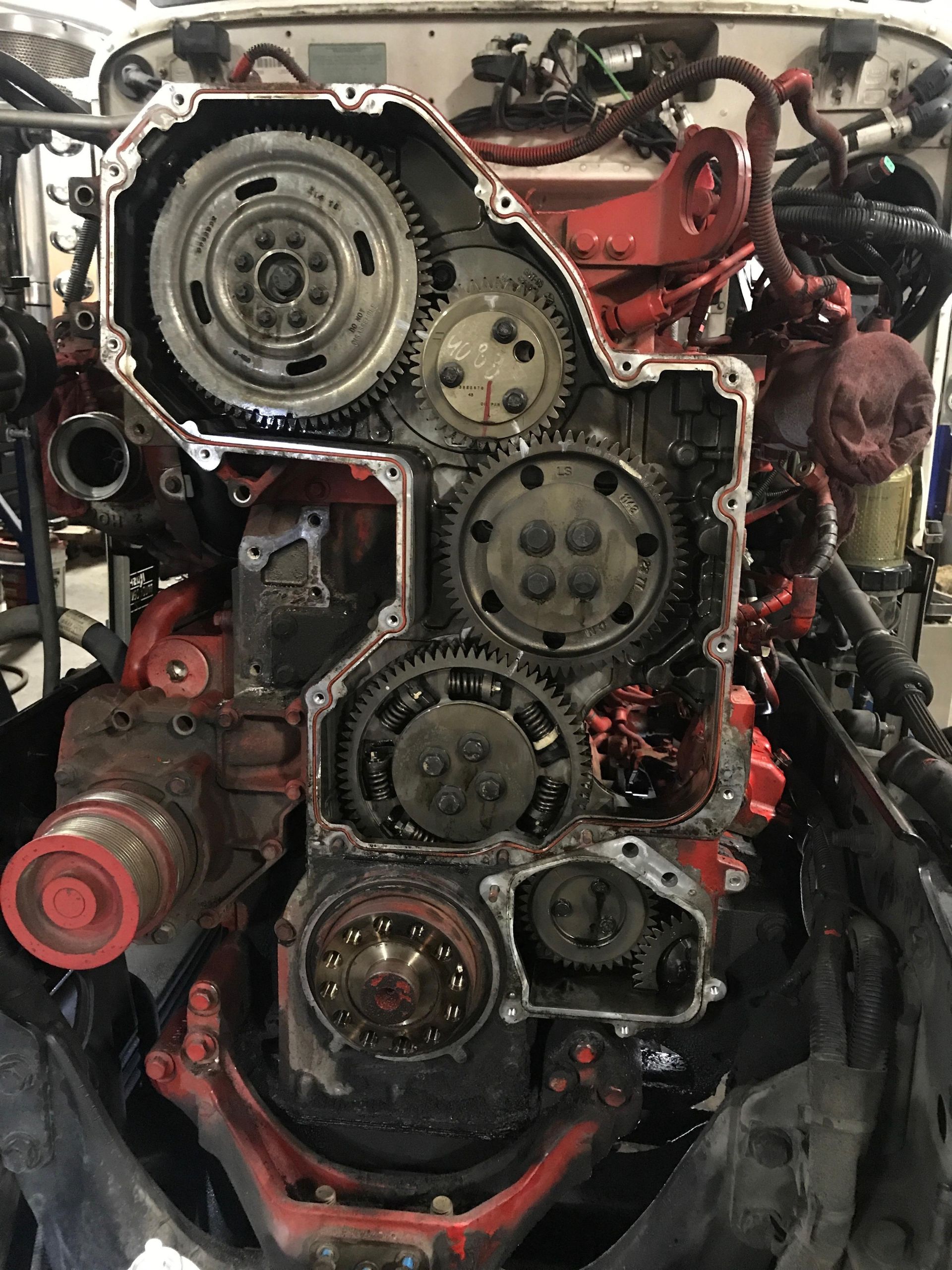 Engine with gears exposed; red and black; mechanical components visible.