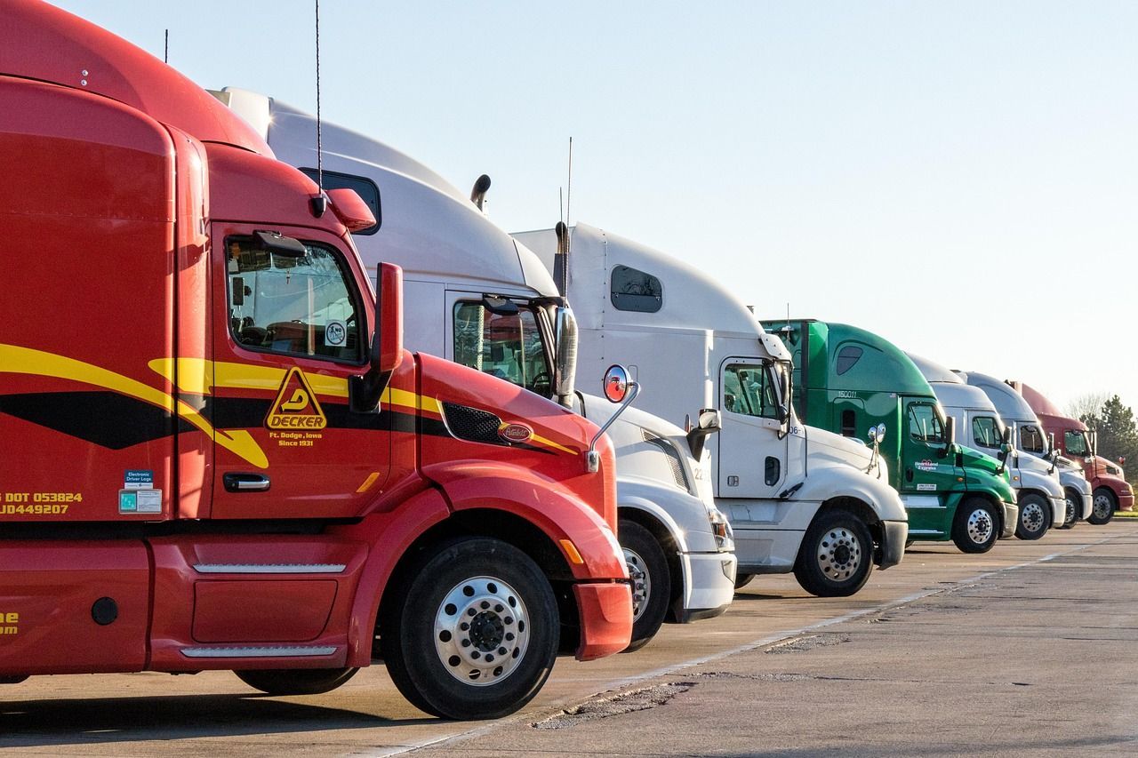 Line of semi-trucks parked outdoors; red, white, green, and other colors visible.