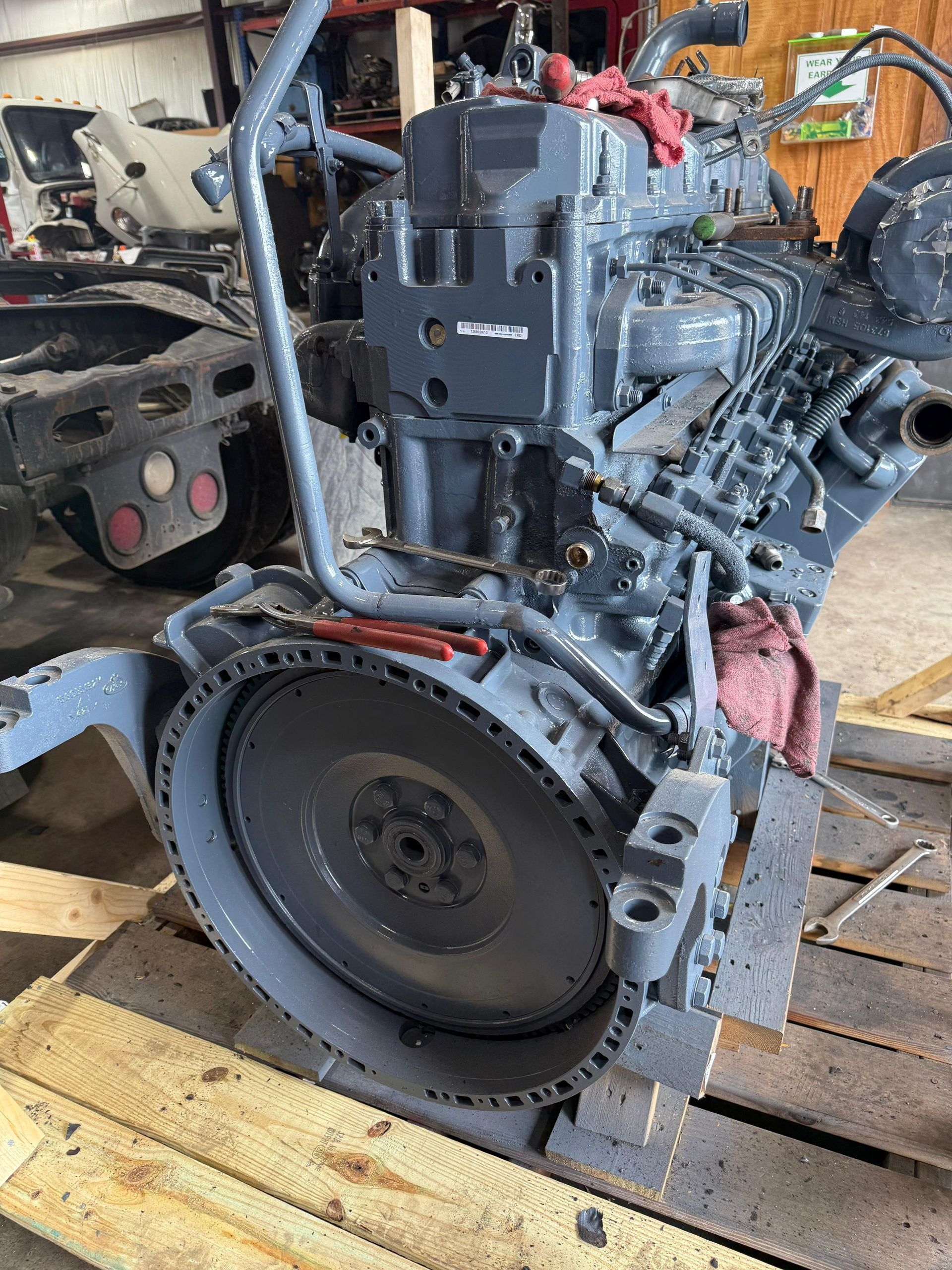 Gray diesel engine on a wooden pallet in a workshop.