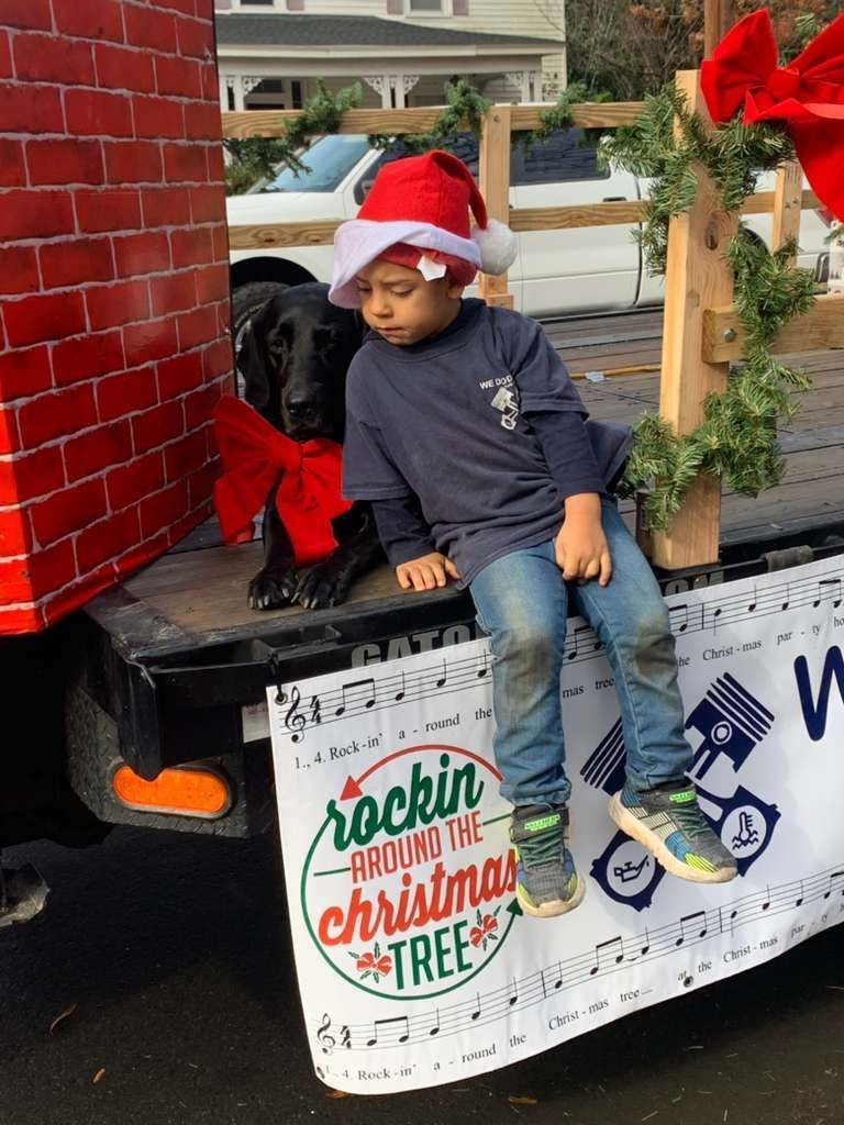 Boy in Santa hat, dog with bow, on Christmas float, 