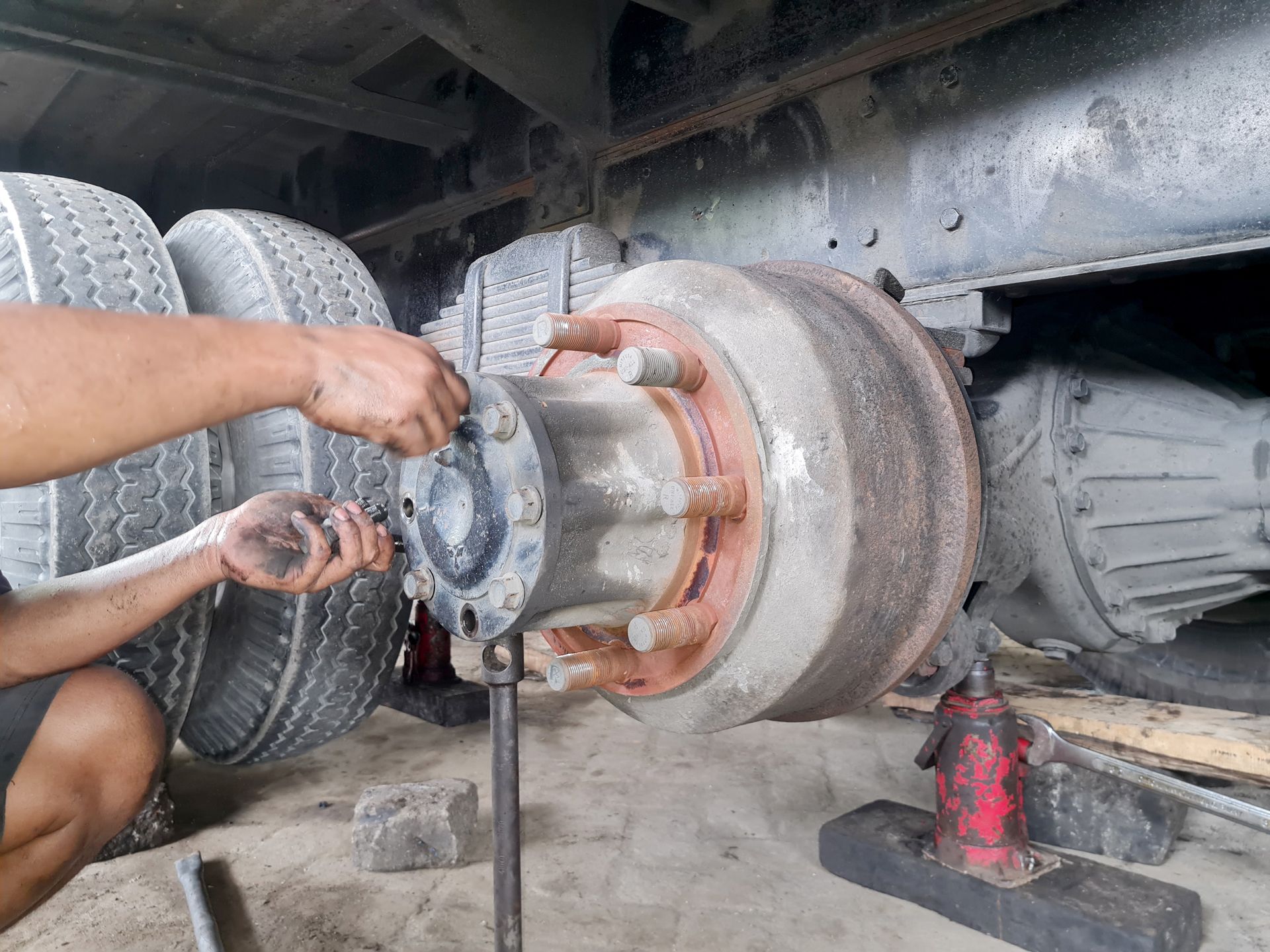 A mechanic working on a truck's wheel assembly. 