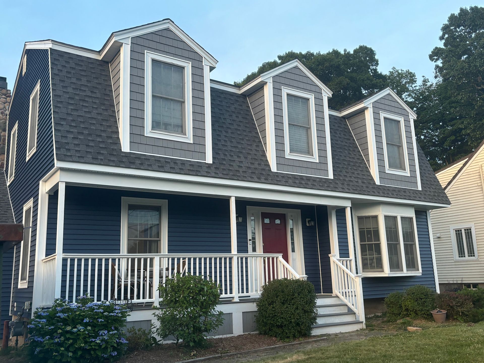 A blue house with a white porch and a red door