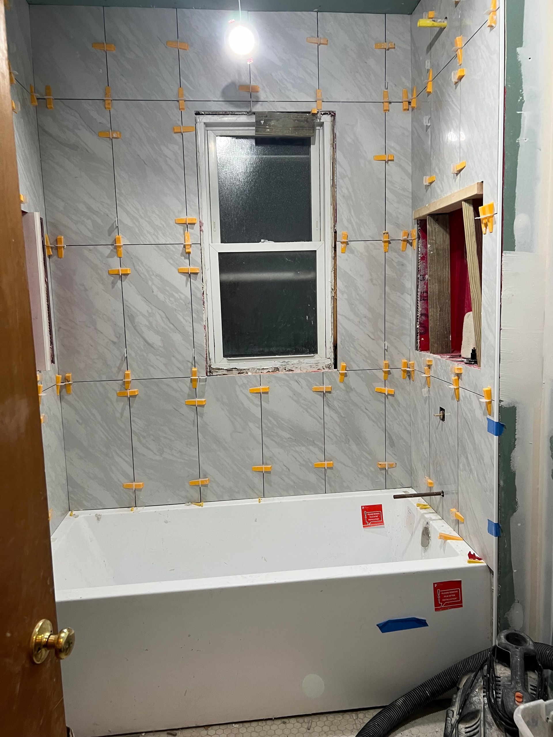 A bathroom under construction with a bathtub and a window.