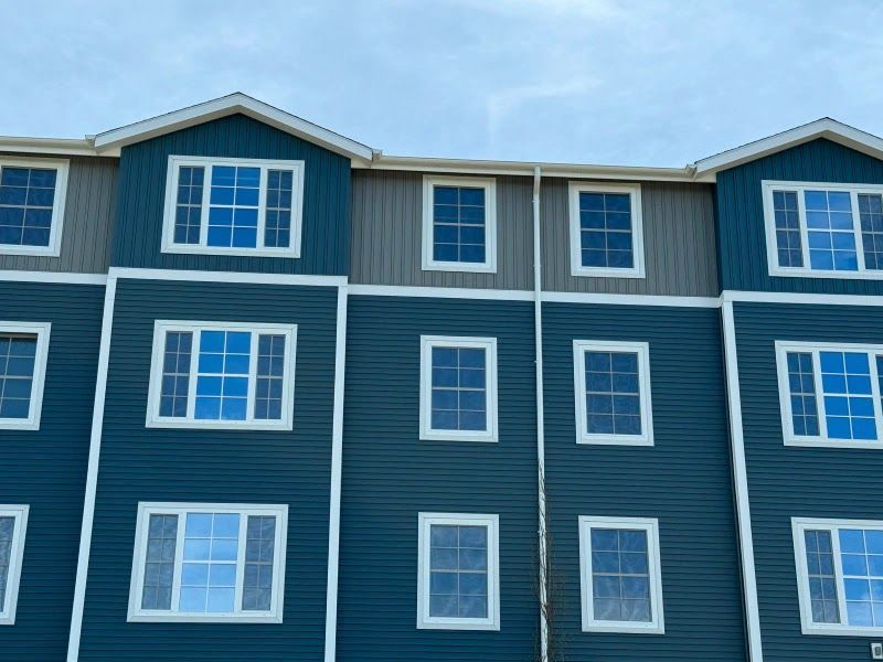 A blue and gray apartment building with lots of windows