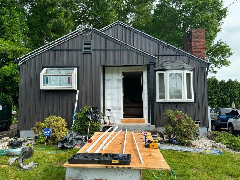 A black house with a white door is being remodeled.