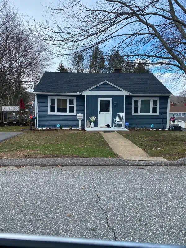 A small blue house with a blue roof and a white porch.