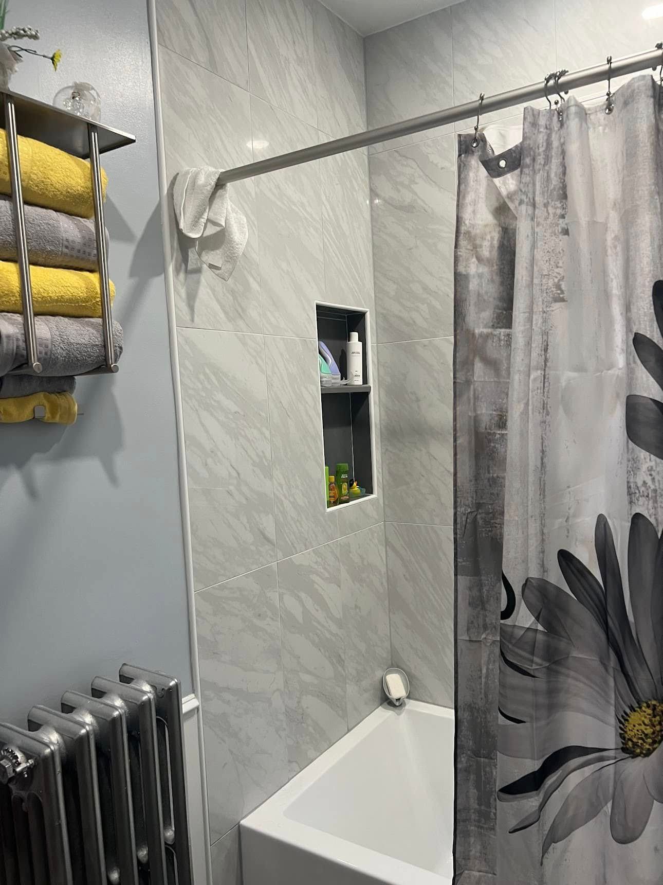Bathroom with grey and yellow towels, tiled walls, shower curtain, and a radiator.
