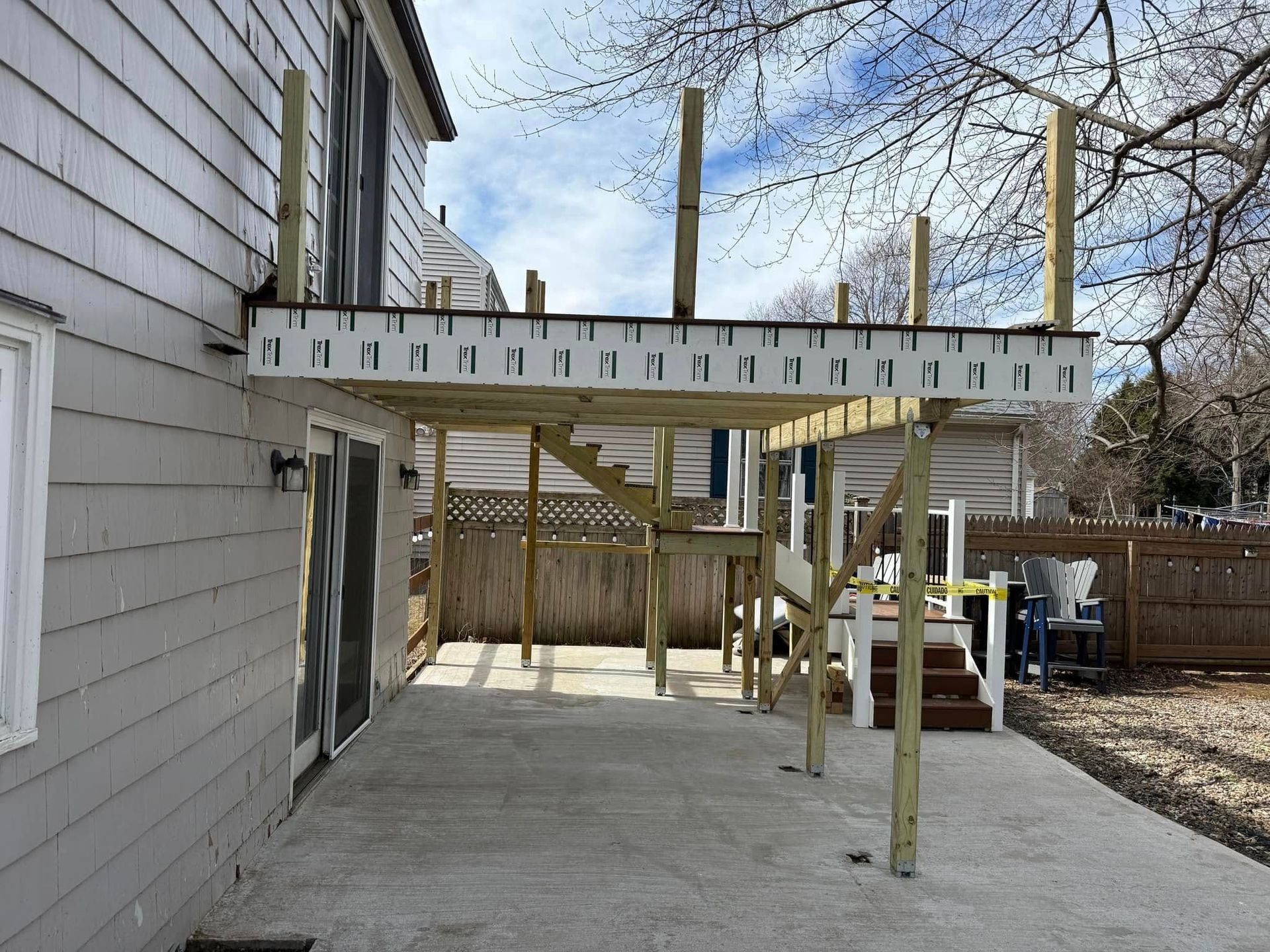 Construction of a wooden deck attached to a house. Wooden posts and frame support a partially completed platform.