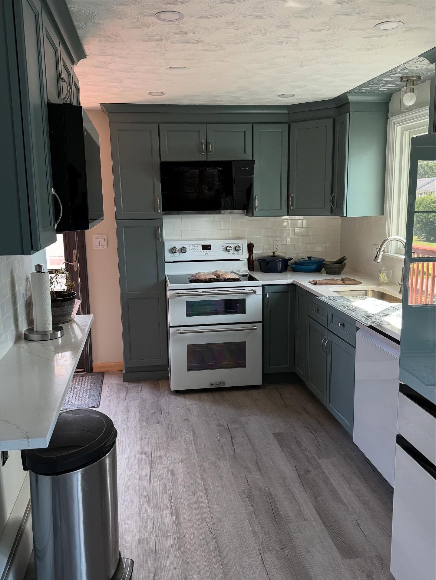 Gray-blue kitchen cabinets, white appliances, and light gray flooring.