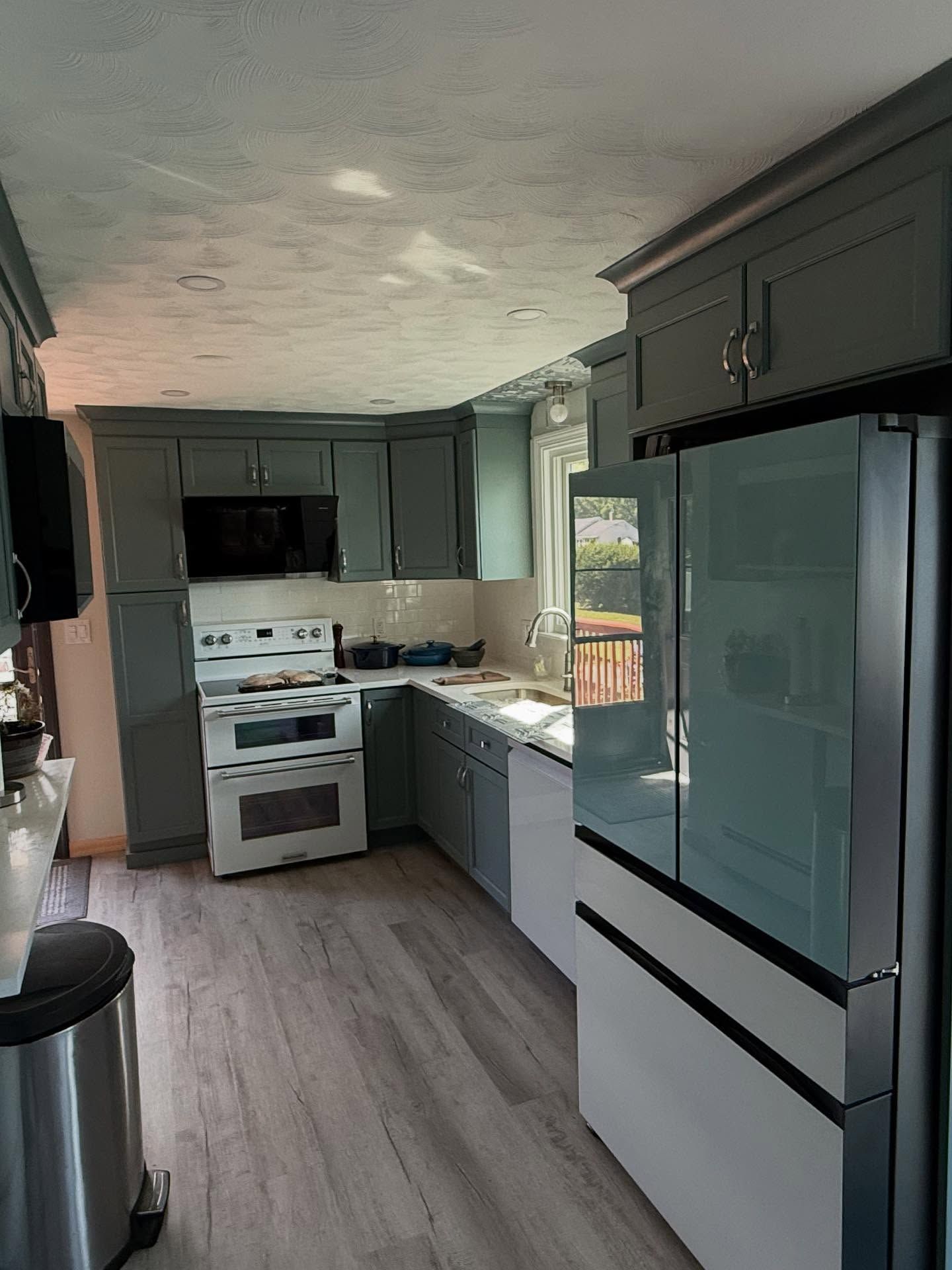Kitchen with gray cabinets, white appliances, and gray flooring.