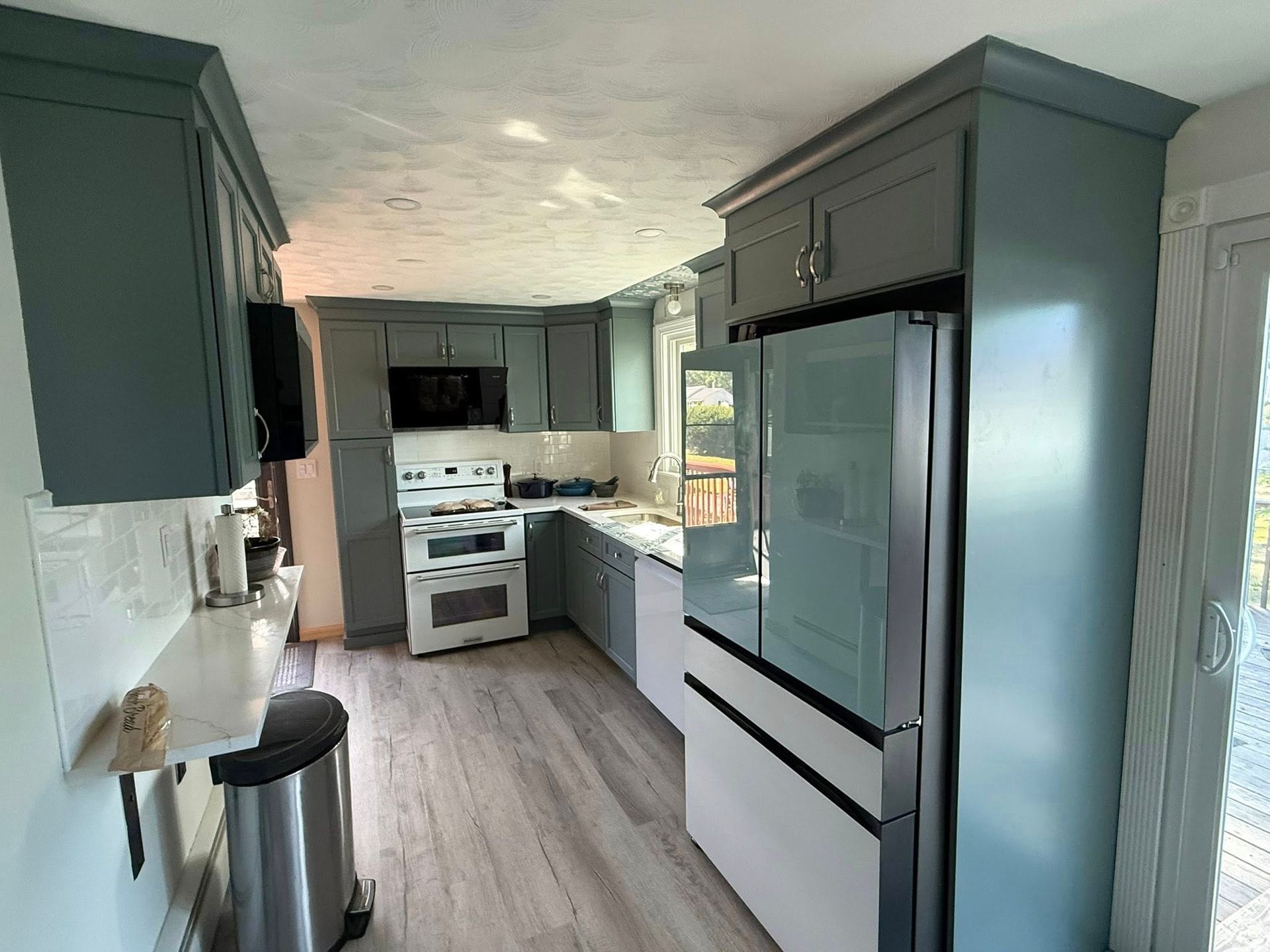 Kitchen with gray cabinets, white appliances, and light wood flooring.