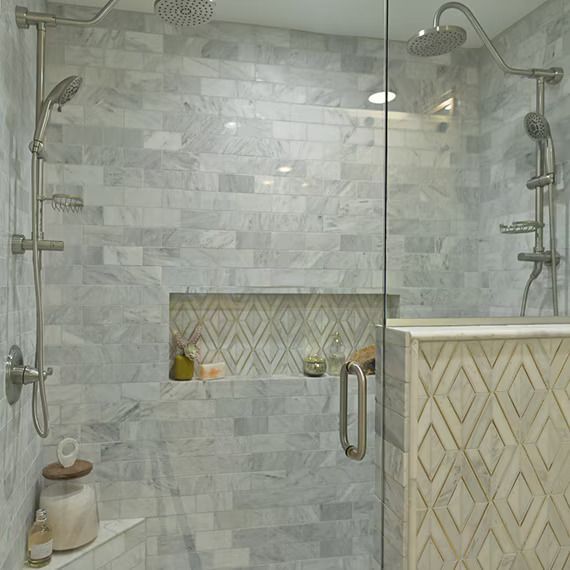 Shower with gray marble tile, glass door, and built-in niche; stainless steel fixtures and showerheads.