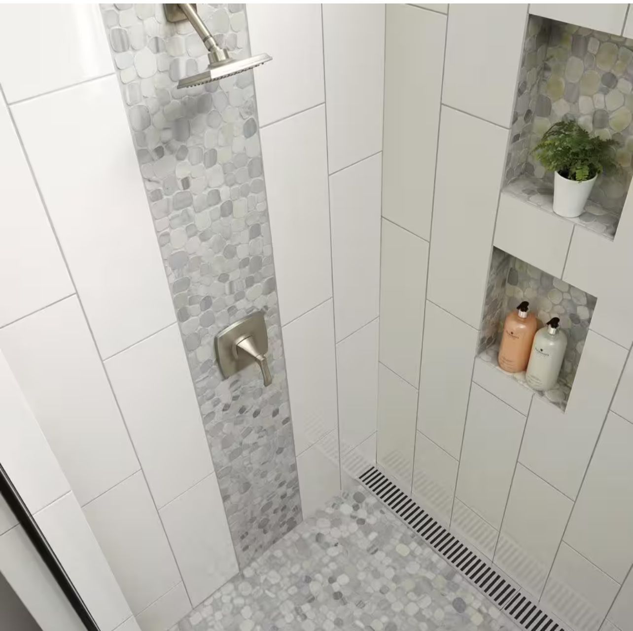 Modern white tiled shower with mosaic accent strip, built-in shelves, and pebble floor.