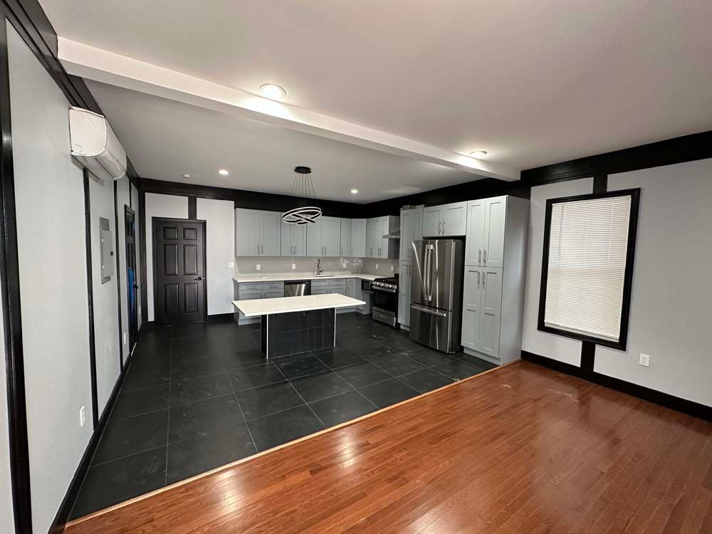 Open-concept kitchen/living area with gray cabinets, stainless steel appliances, and dark trim.