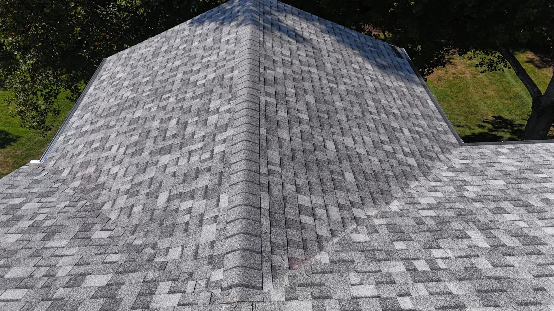 Gray shingle roof, angled view. Building exterior with tree in the background.