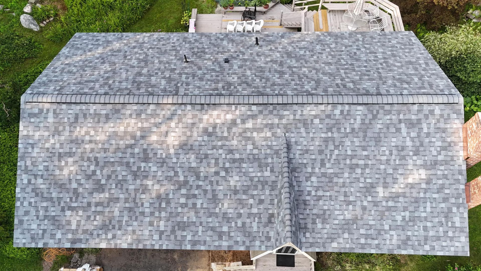 Overhead view of a house with a gray asphalt shingle roof surrounded by green grass.