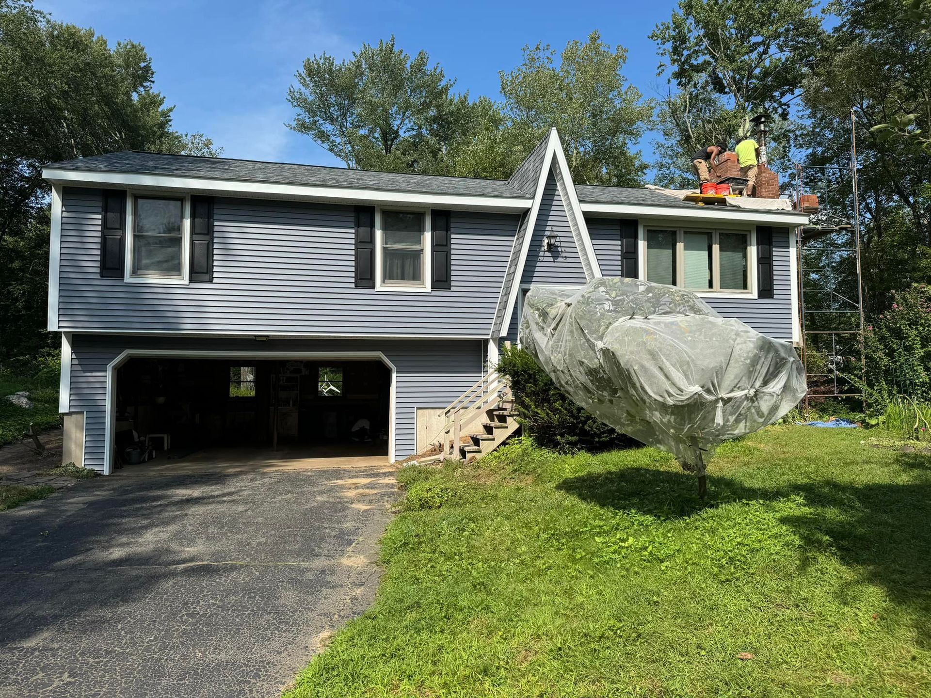 House with blue siding and workers on roof.