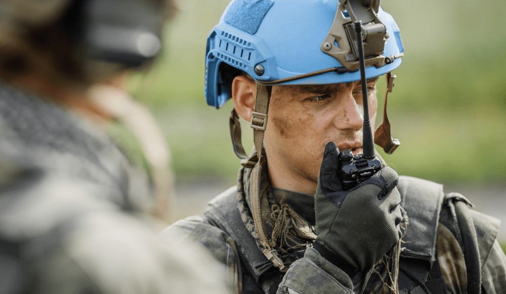A man in military gear talking on a walkie talkie