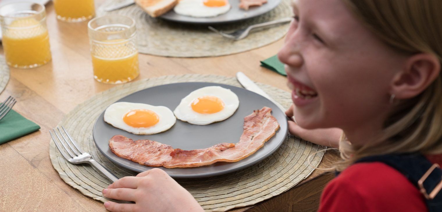 A child eating a plate of food placed like a smiling face