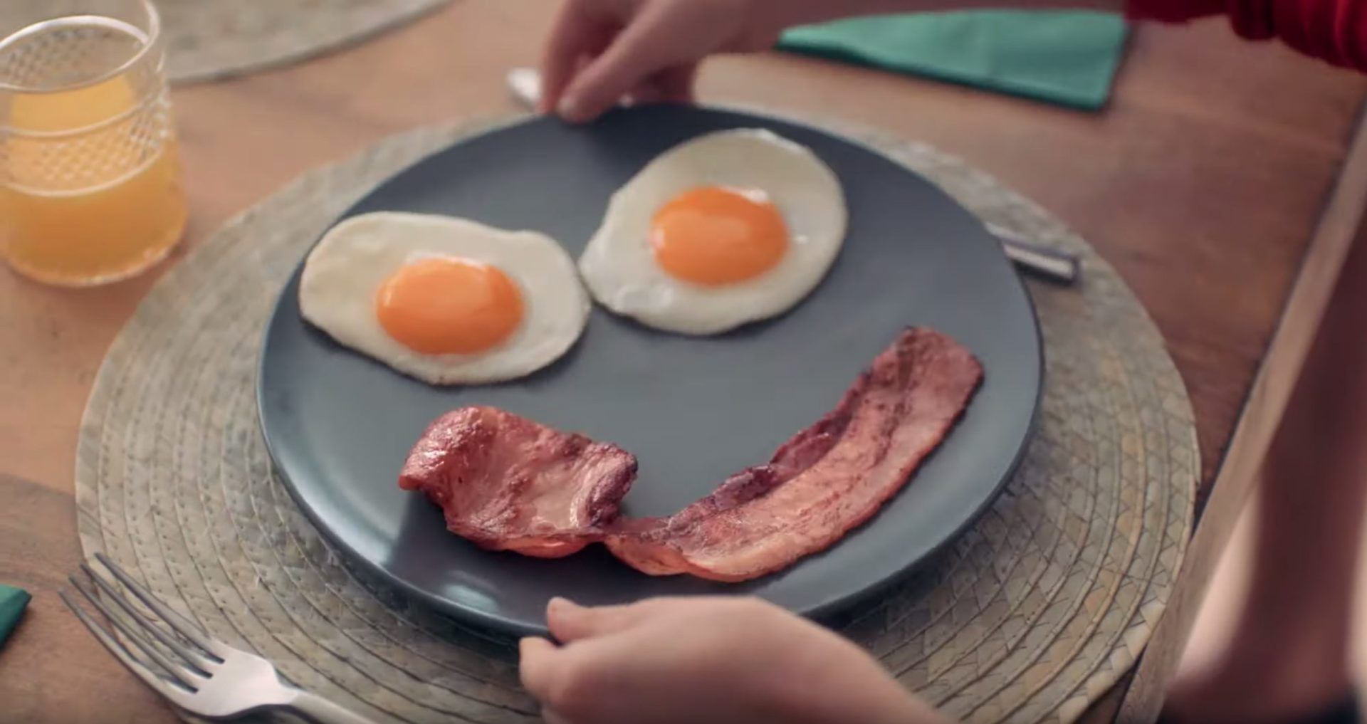 Two eggs and a piece of bacon laid out on a plate to look like a smiling face