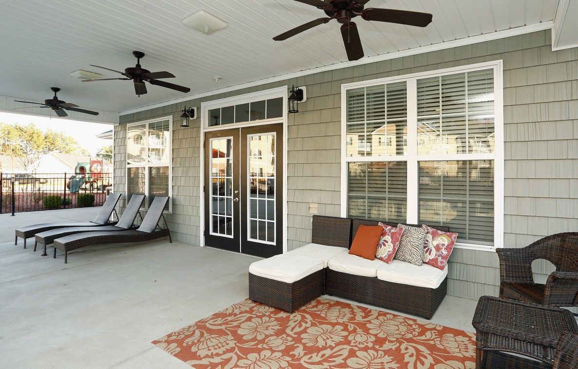 Covered outdoor community patio with wicker seating, cushions, and ceiling fans at Jack Britt.