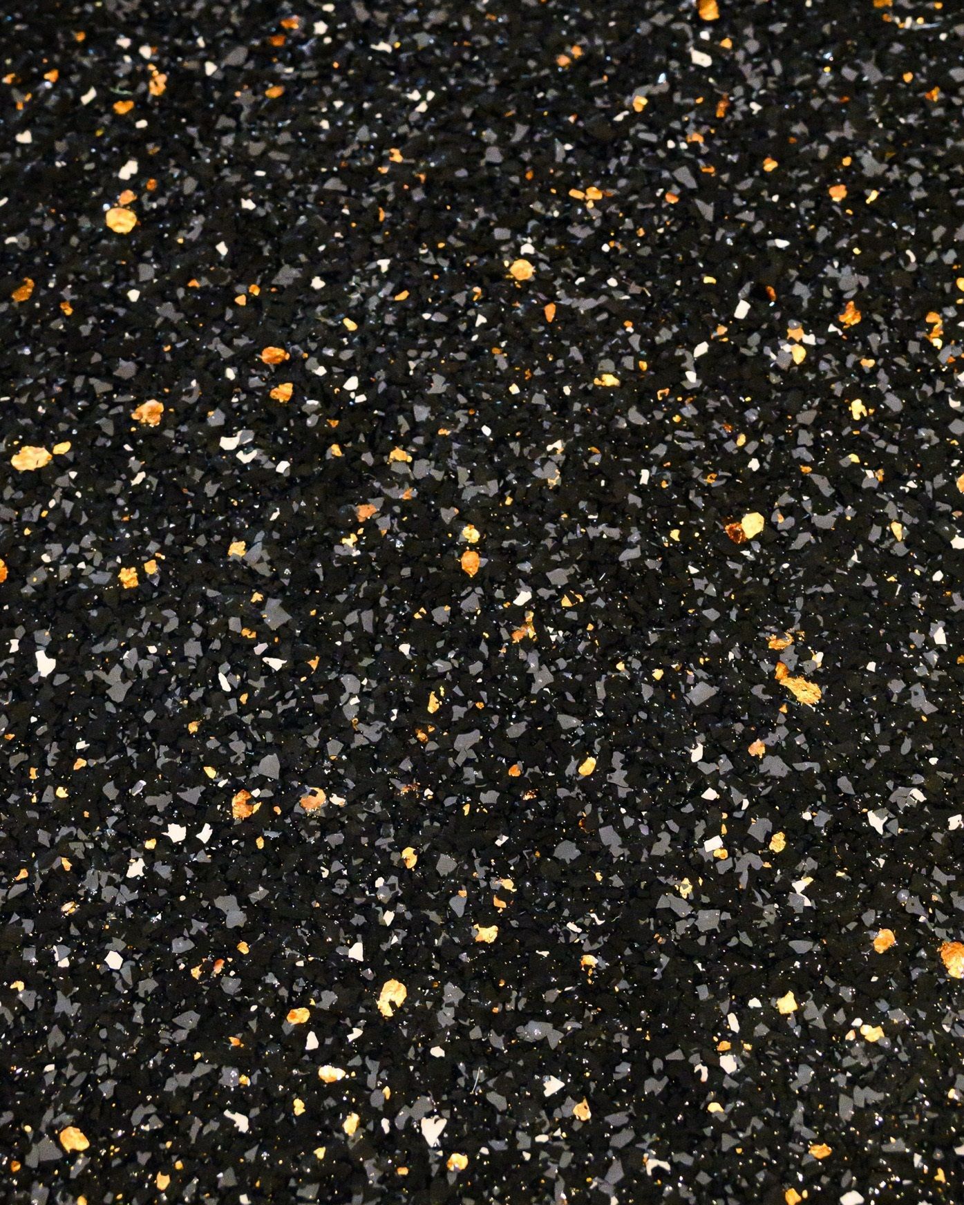 A close up of a black and gold glitter surface.