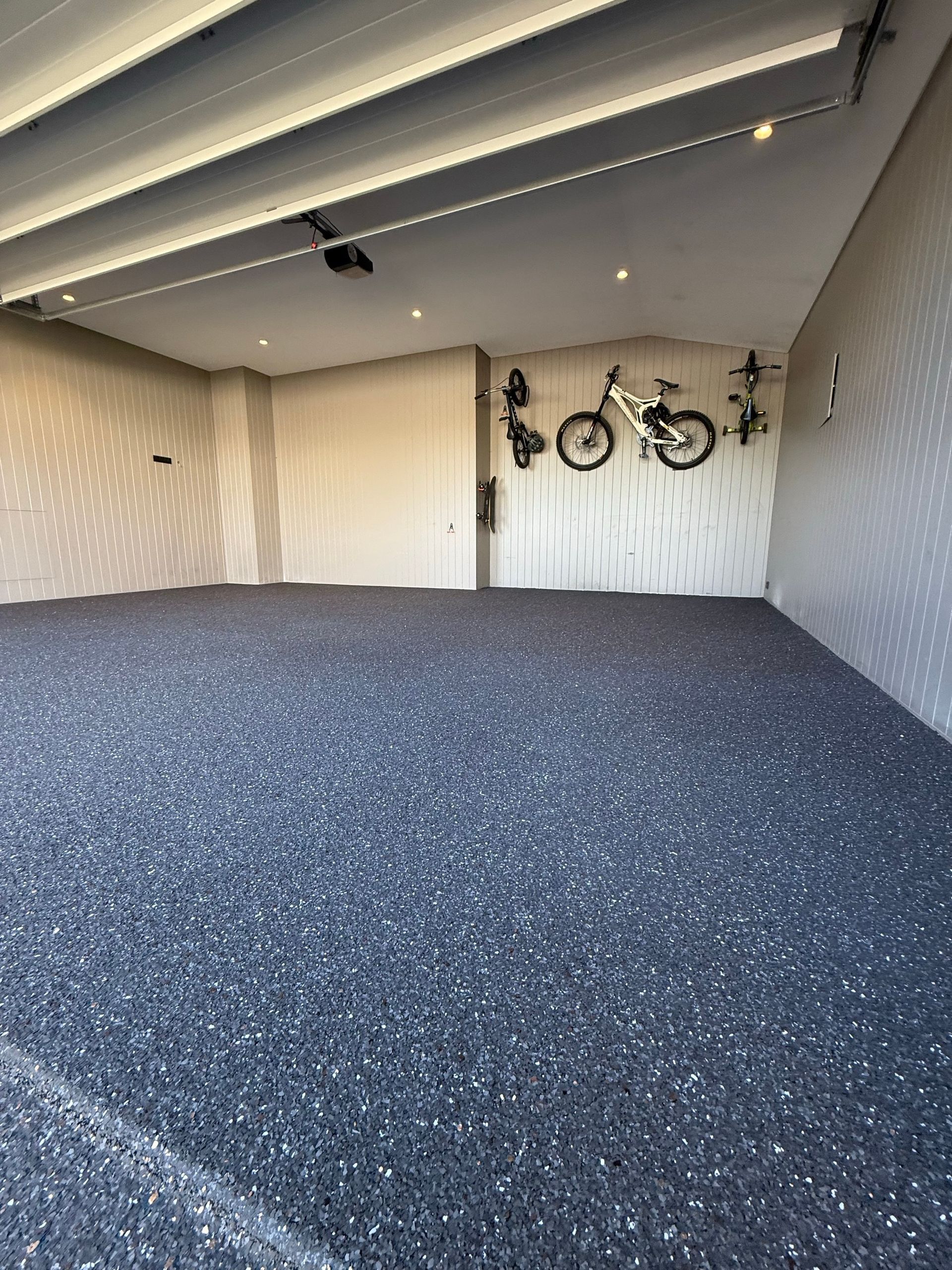 A garage with bikes hanging on the wall and a carpeted floor