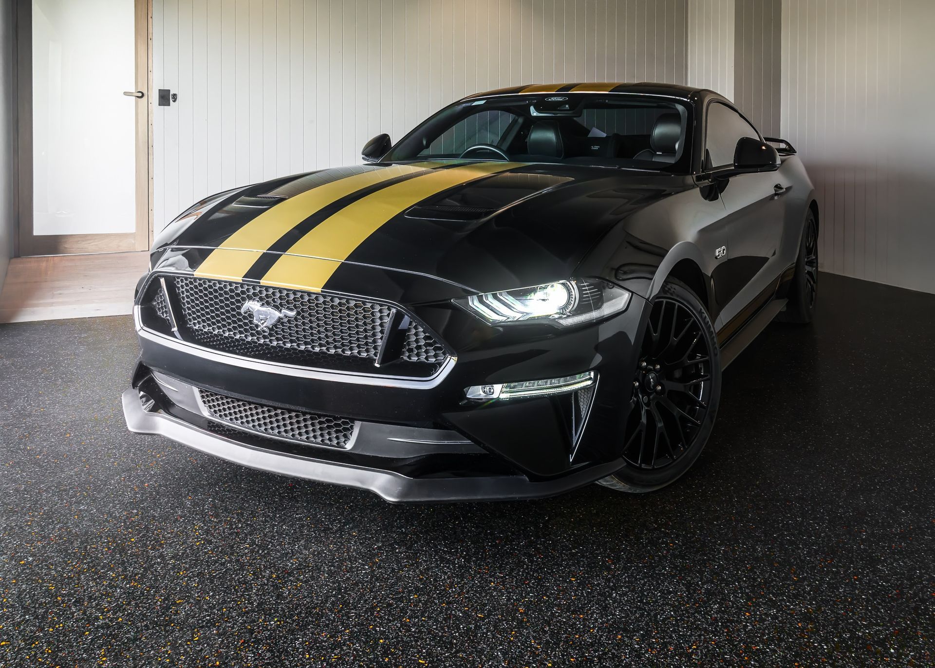 A black and yellow mustang is parked in a garage.