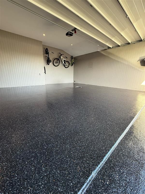 A garage with bikes hanging on the wall and a black floor.