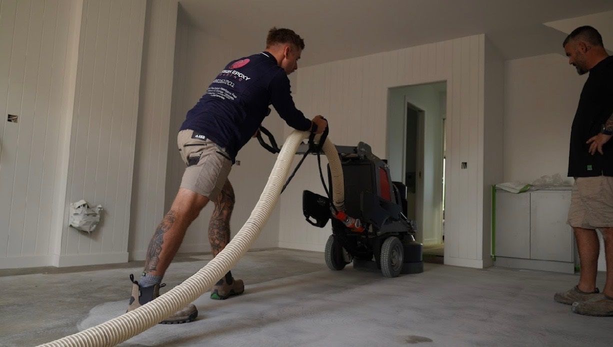 A man is using a vacuum cleaner to clean a concrete floor efficiently.