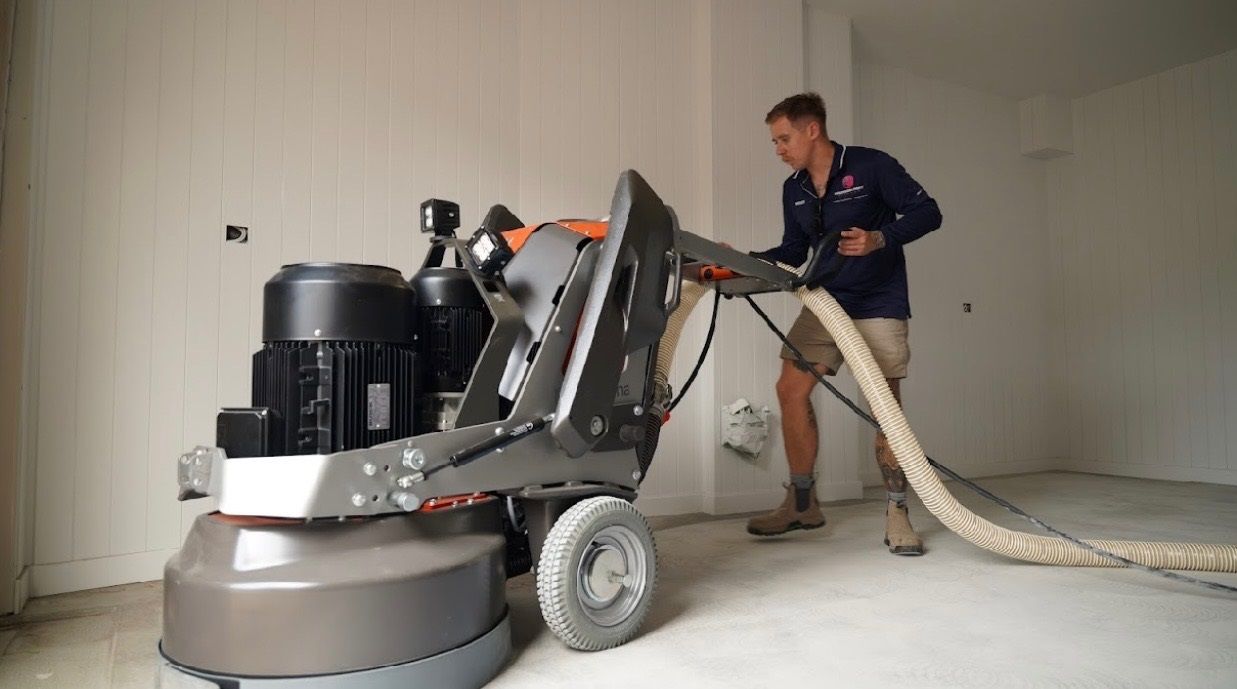 A man is using a machine to polish the floor in a room.