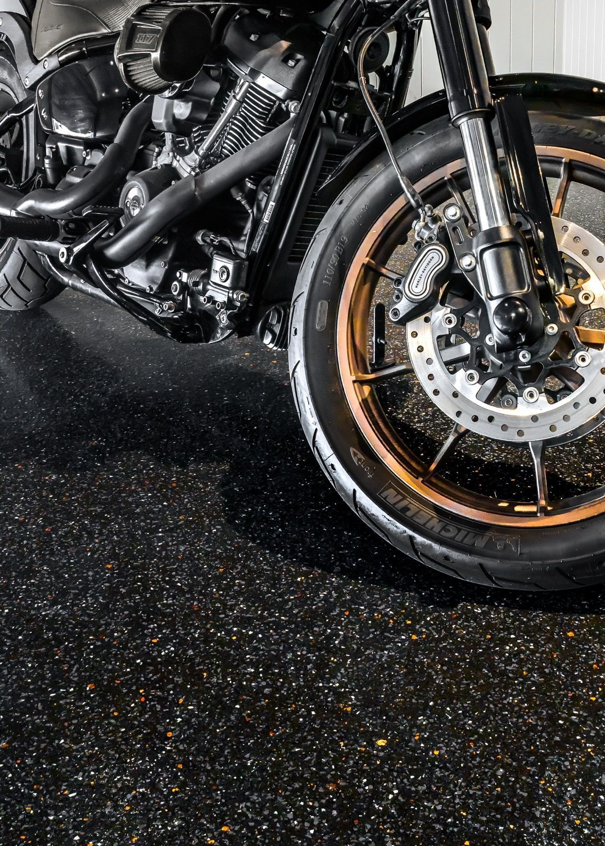A close up of a motorcycle 's front wheel on a black surface.