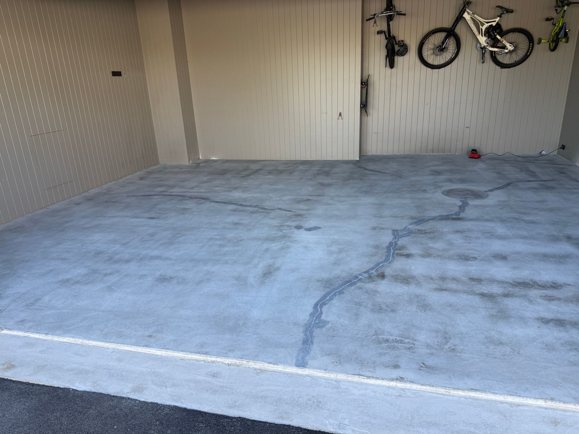 Two bikes are hanging on the wall of a garage.