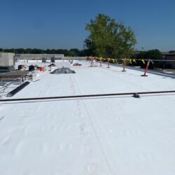White commercial roof with safety equipment under a blue sky.