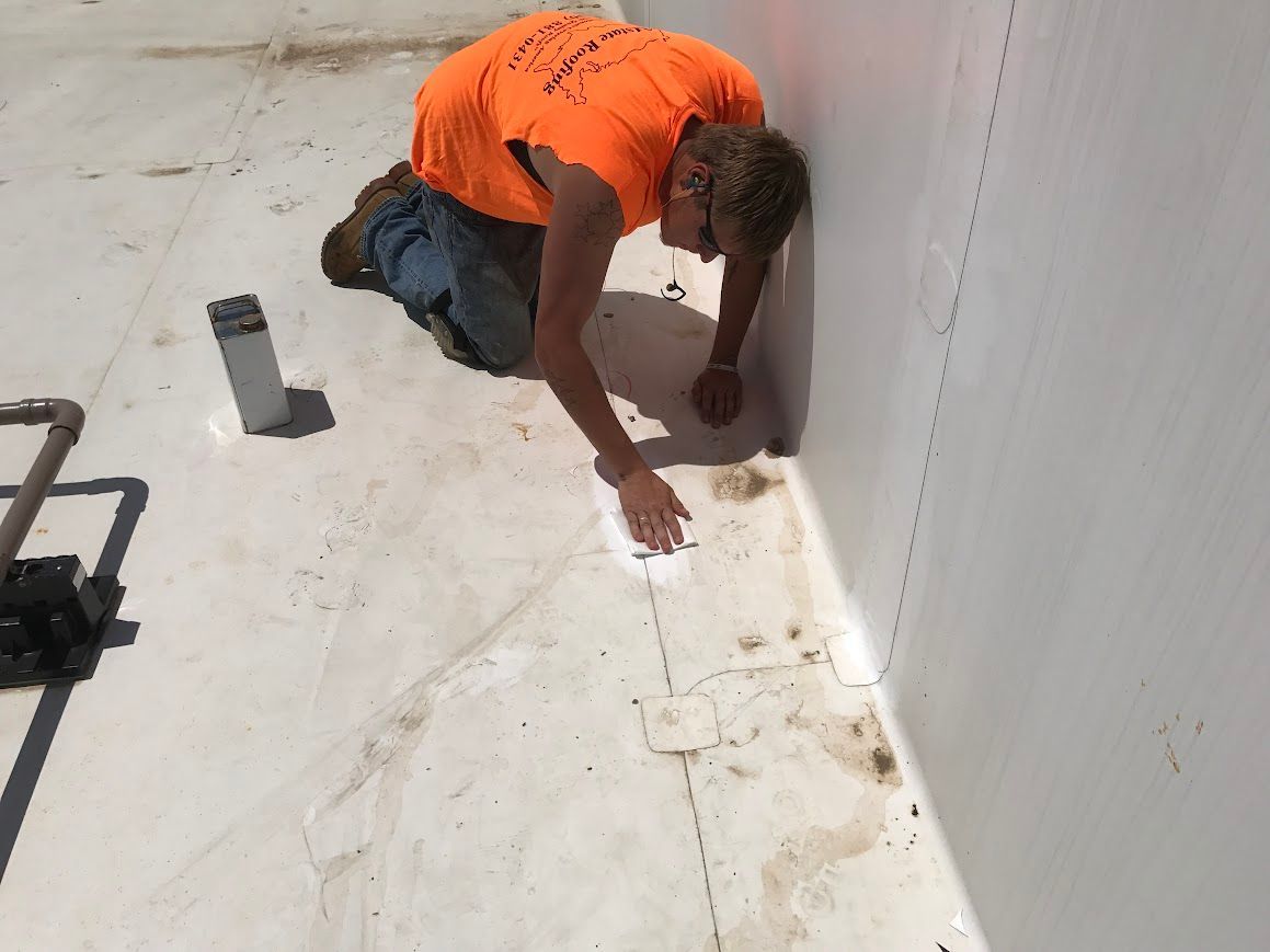 Four workers in orange suits installing solar panels on a building rooftop.