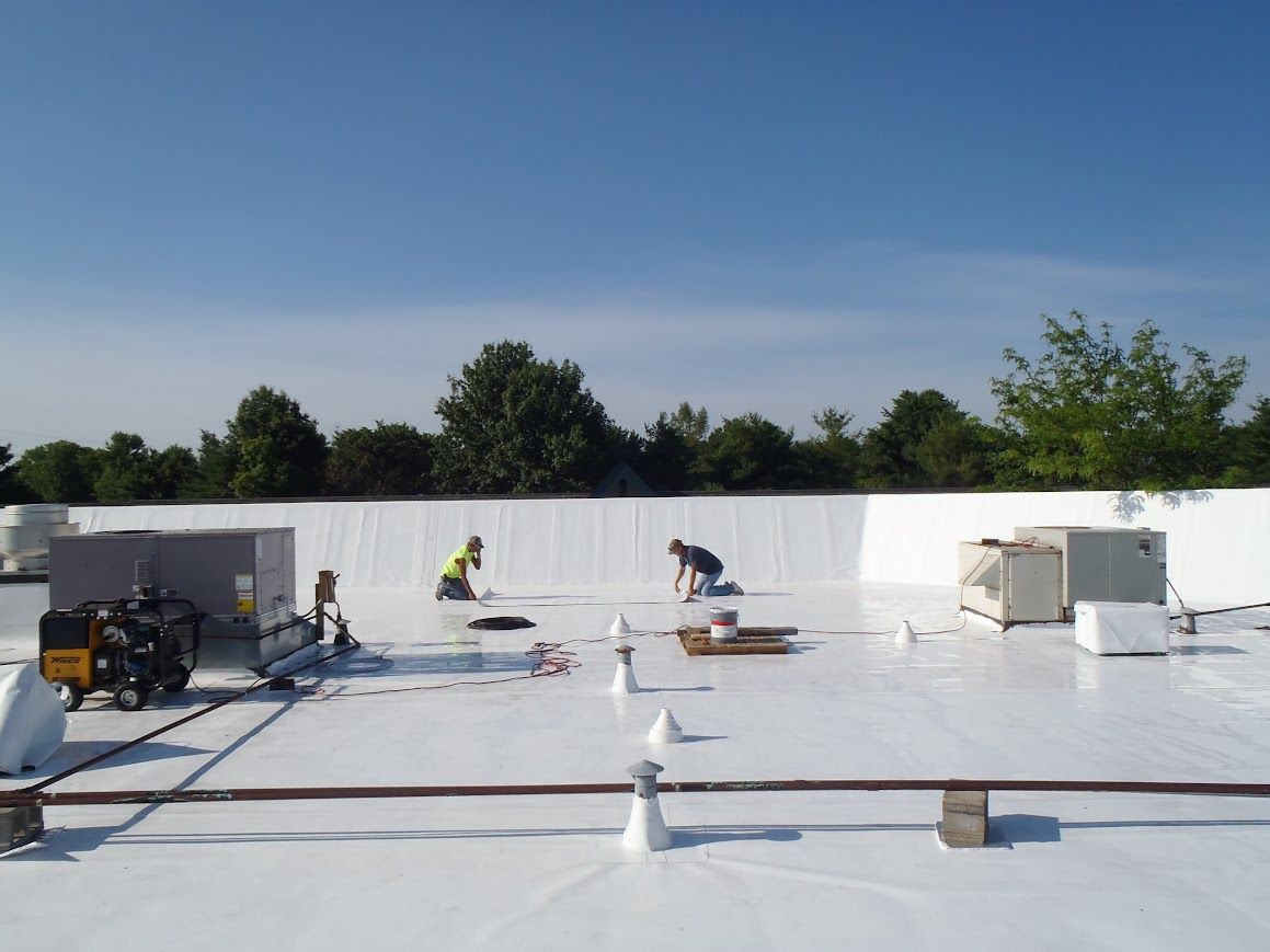 Red barn with a vent on the roof. The roof is silver, and the sky is blue.