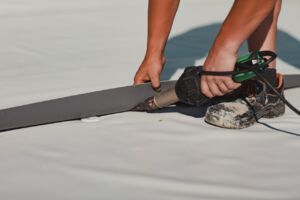 Person using a heat gun to weld a grey strip onto a white surface.