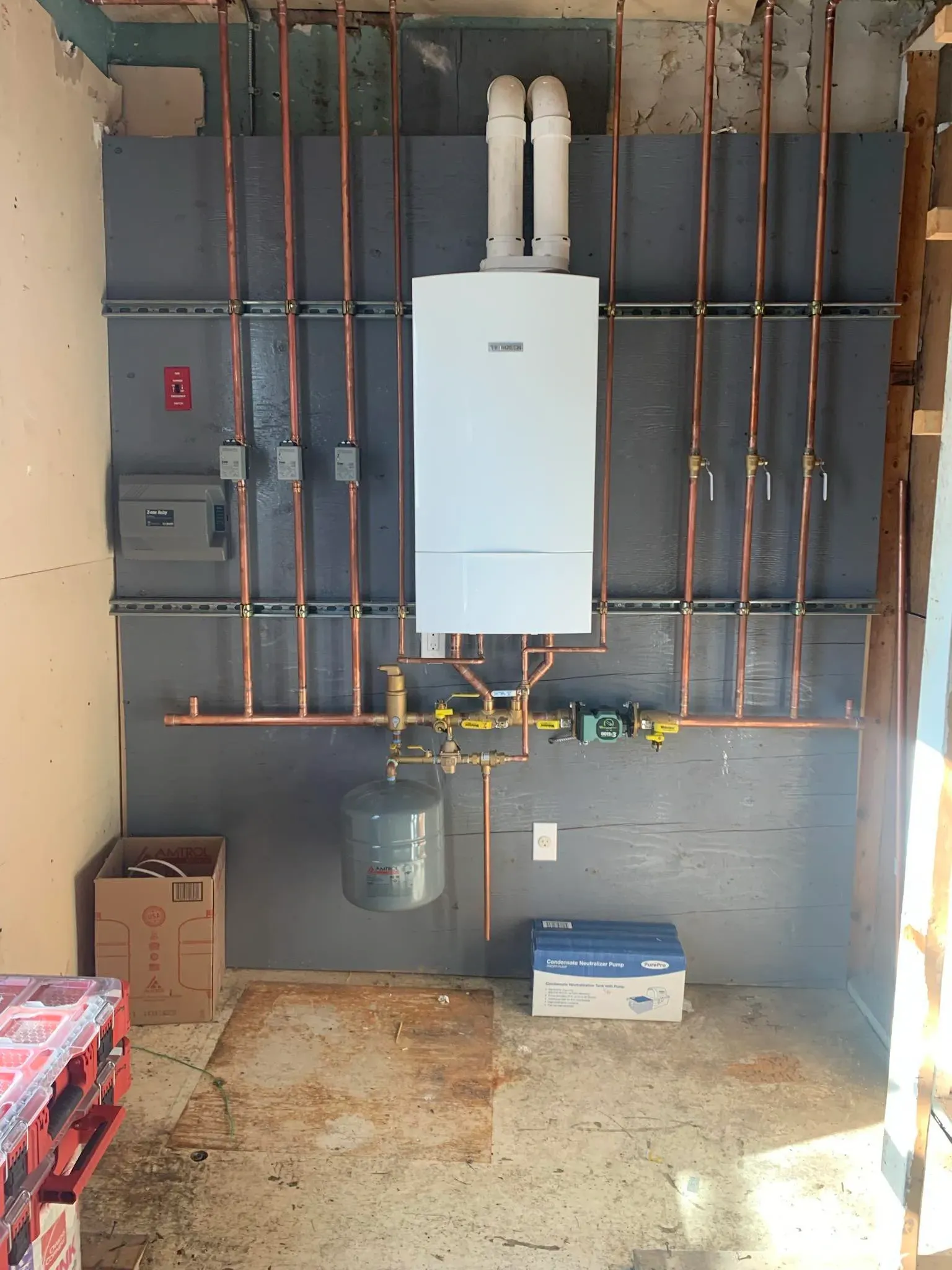 A room with a boiler and copper pipes on the wall.