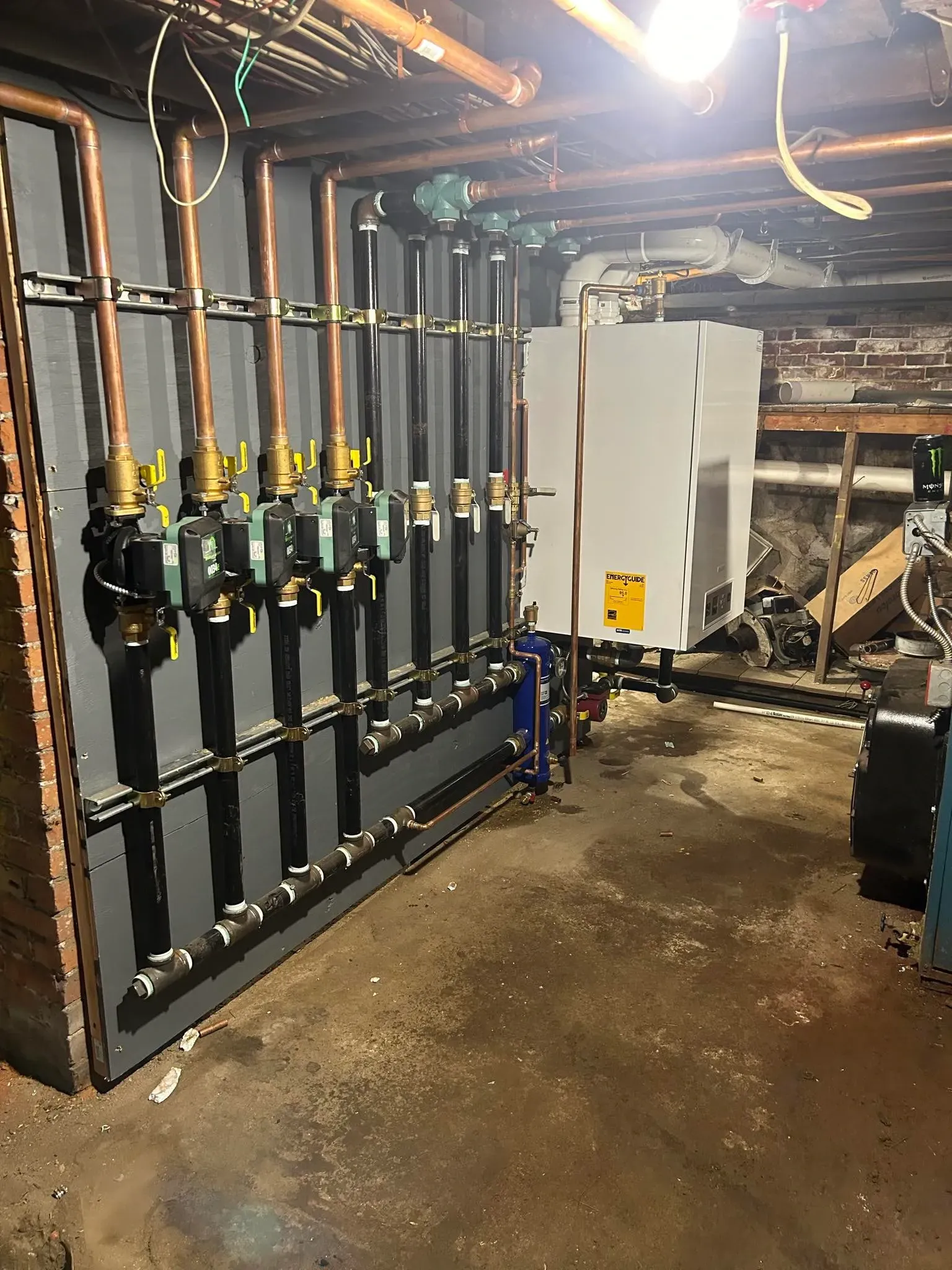 A room with a lot of pipes and a boiler in it.