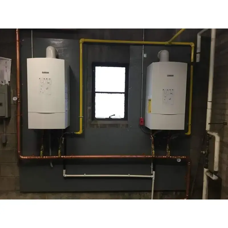 Two white boilers are hanging on a wall next to a window.