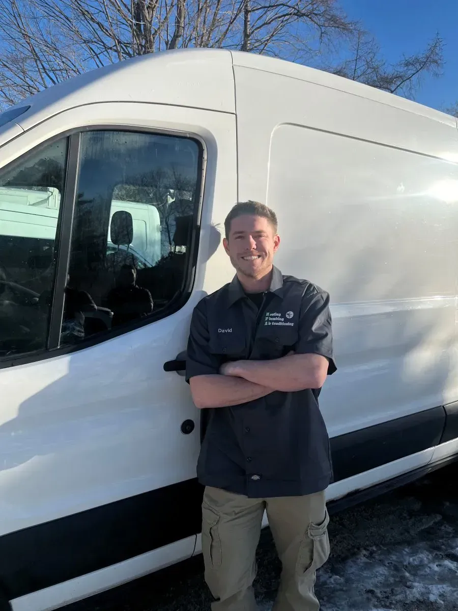 A man is standing in front of a white van with his arms crossed.