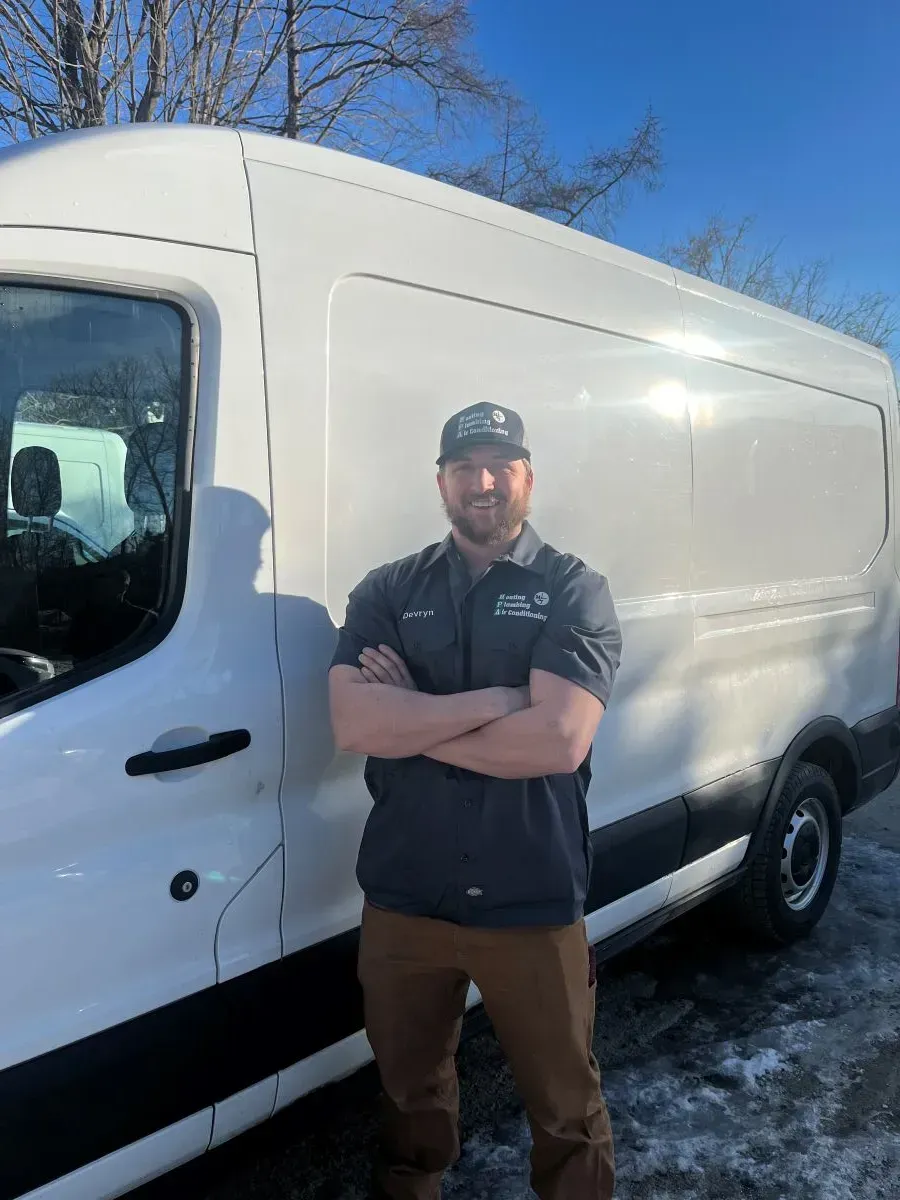 A man is standing in front of a white van with his arms crossed.
