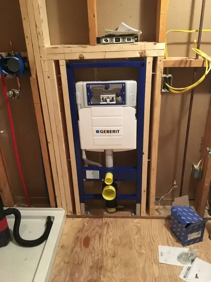 A wall mounted toilet is being installed in a bathroom.