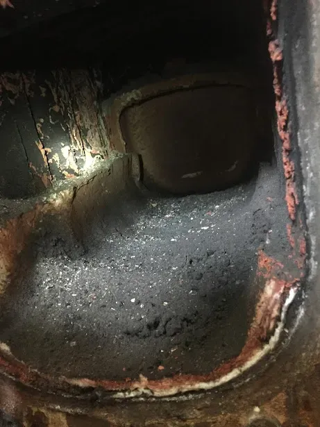 A close up of a rusty metal object with a light shining through it.