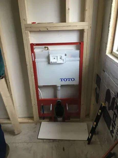 A toilet is being built into a wall in a bathroom.