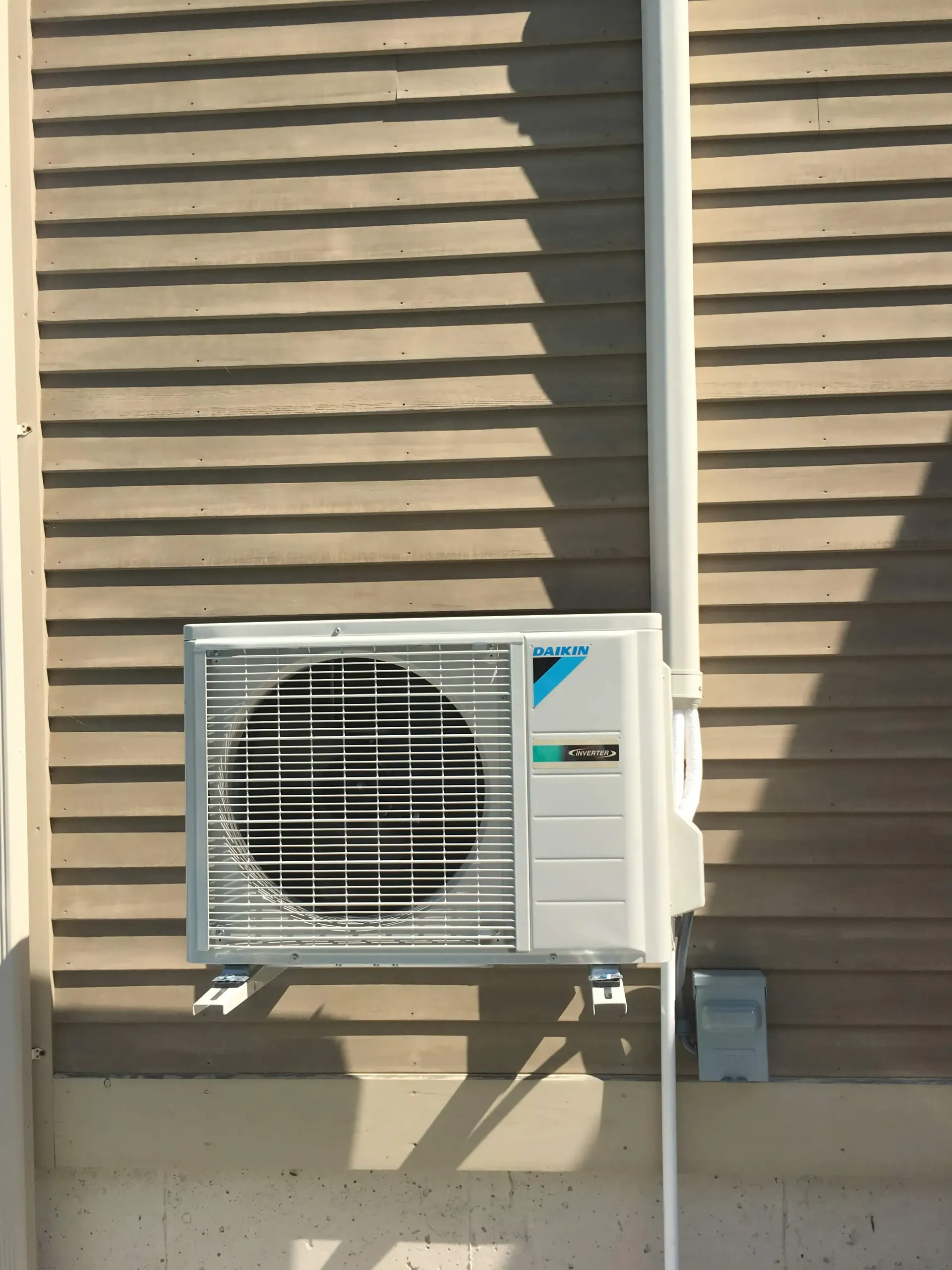 A daikin air conditioner is mounted on the side of a house