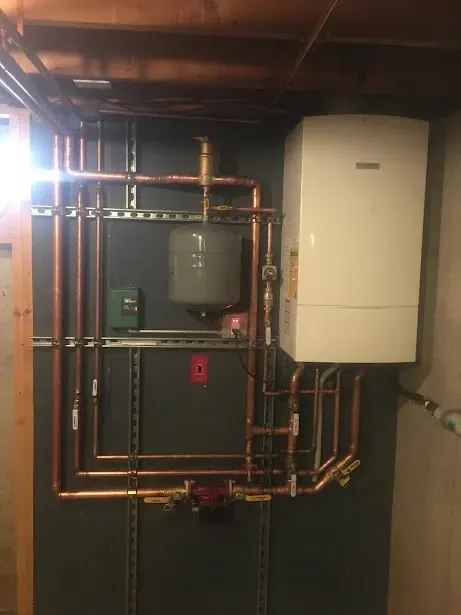 A room with a boiler and copper pipes on the wall